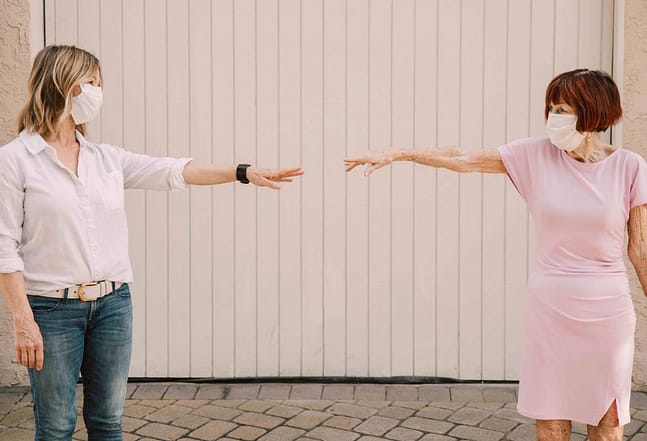 daughter and mom reaching for each other wearing masks during covid-19 pandemic